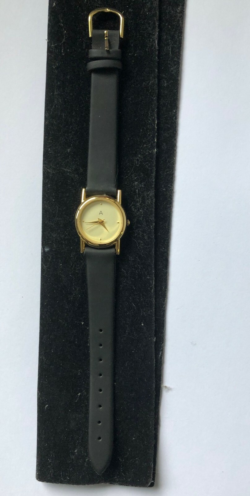 Ladies Avon 101 gold tone dress watch,ivory face,gold hands,black strap.